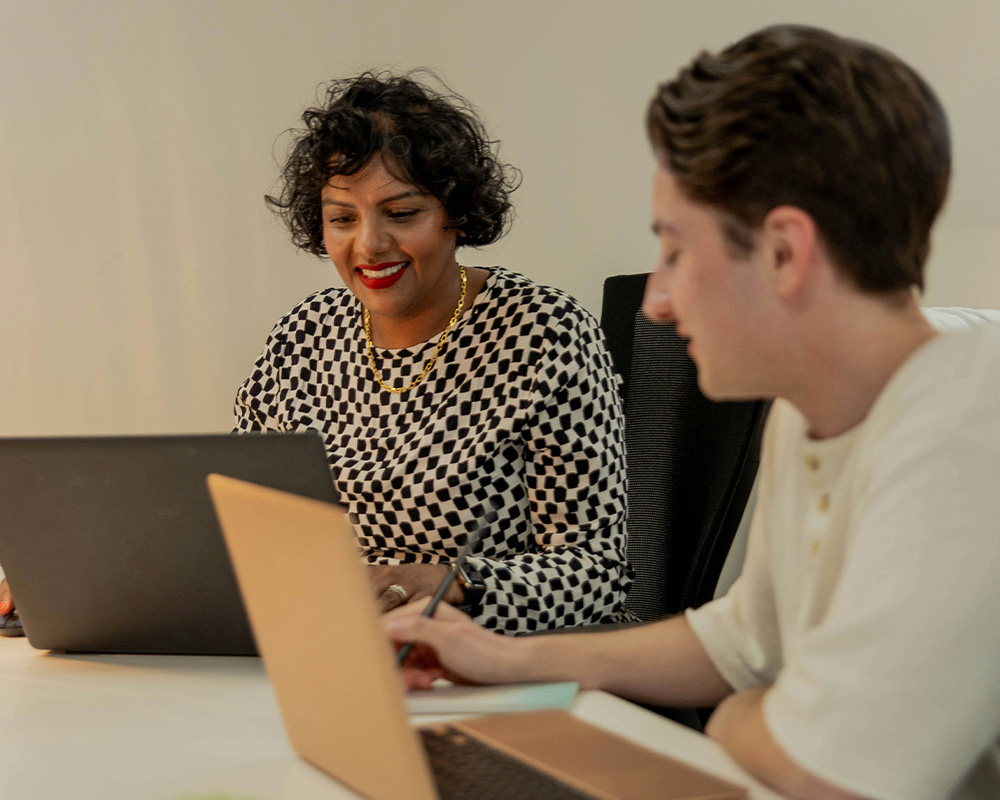 Man and woman smiling at laptops